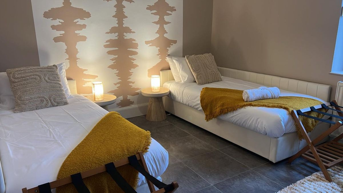 Second bedroom — warm lighting & mustard throws